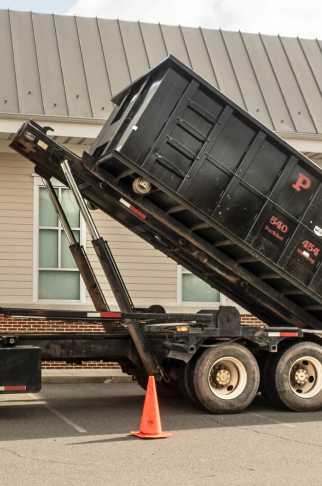 Dumpster being unloaded onto a commercial jobsite
