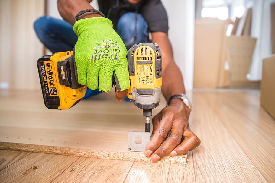 A Man drilling a bracket to wood in a home