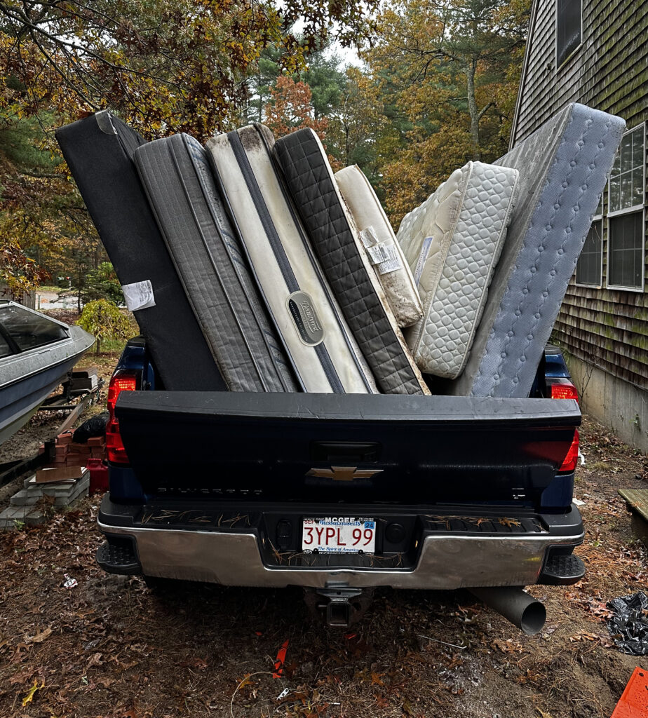 A pickup truck bed loaded with old mattresses