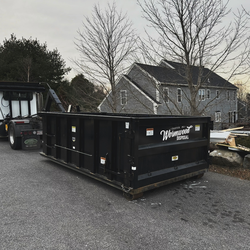 15 Yard black dumpster with Wormwood Disposal logo in a driveway in kingston ma