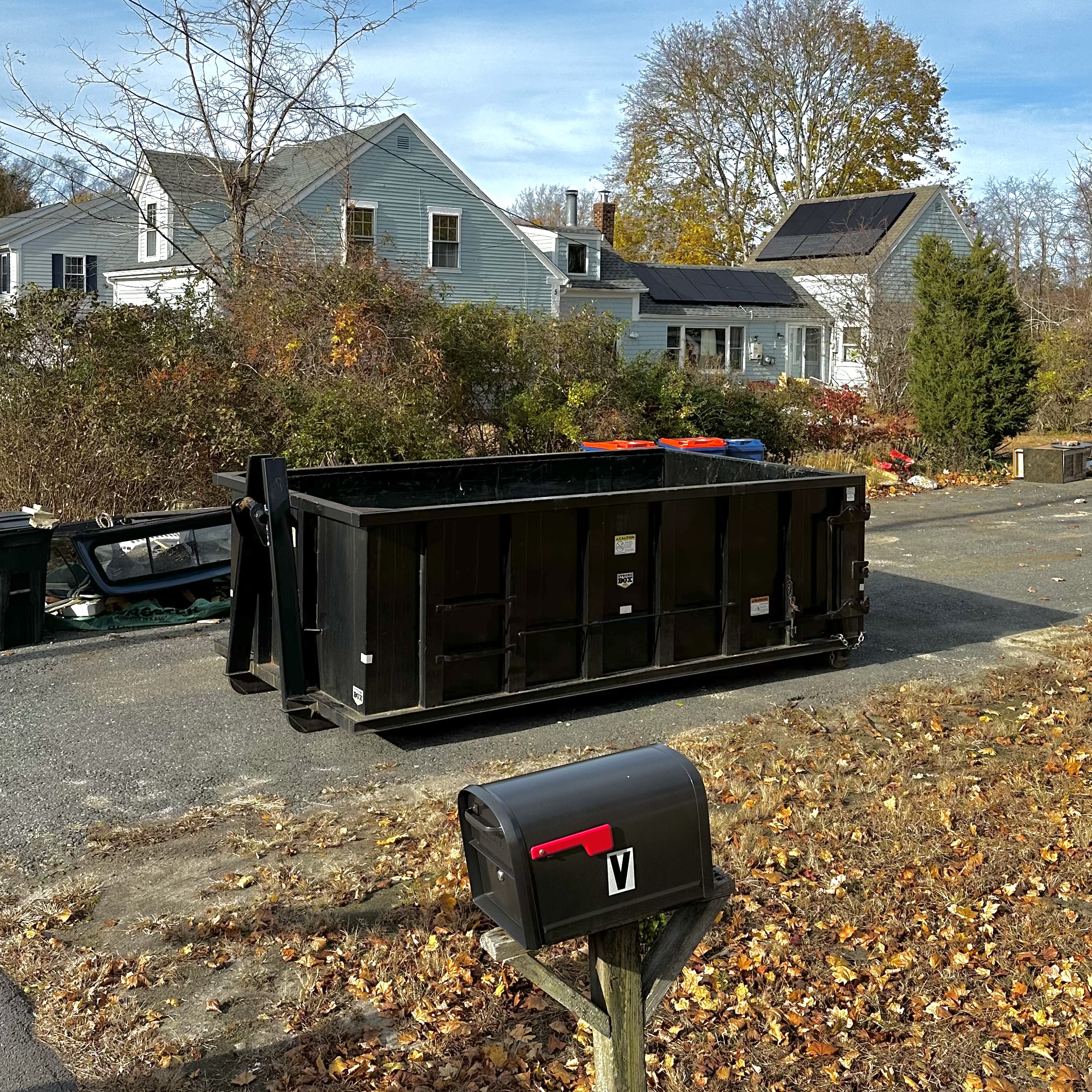 a black 15 yard dumpster sitting empty in a driveway