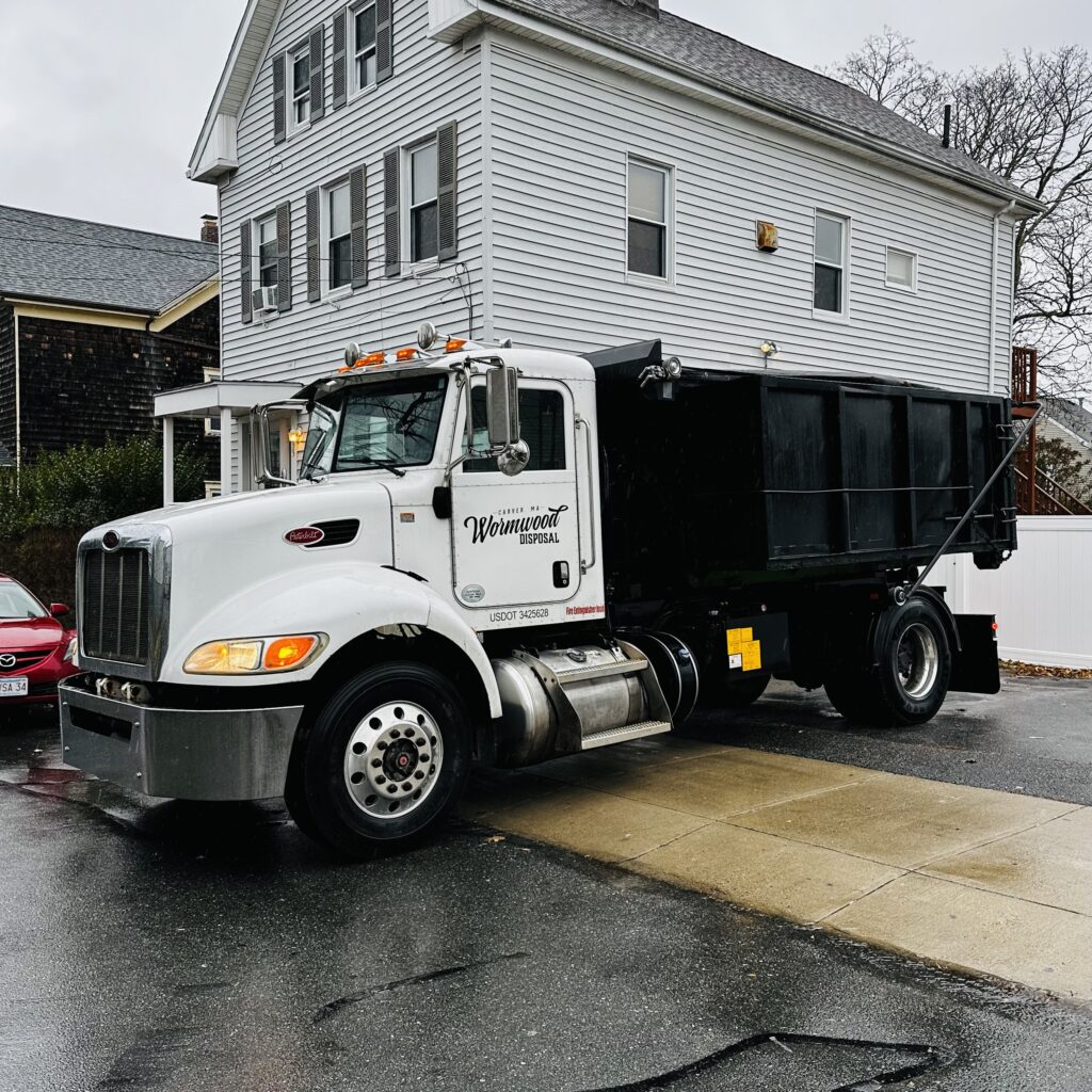 Wormwood Disposal truck loaded with a full dumpster leaving a home in New Bedford