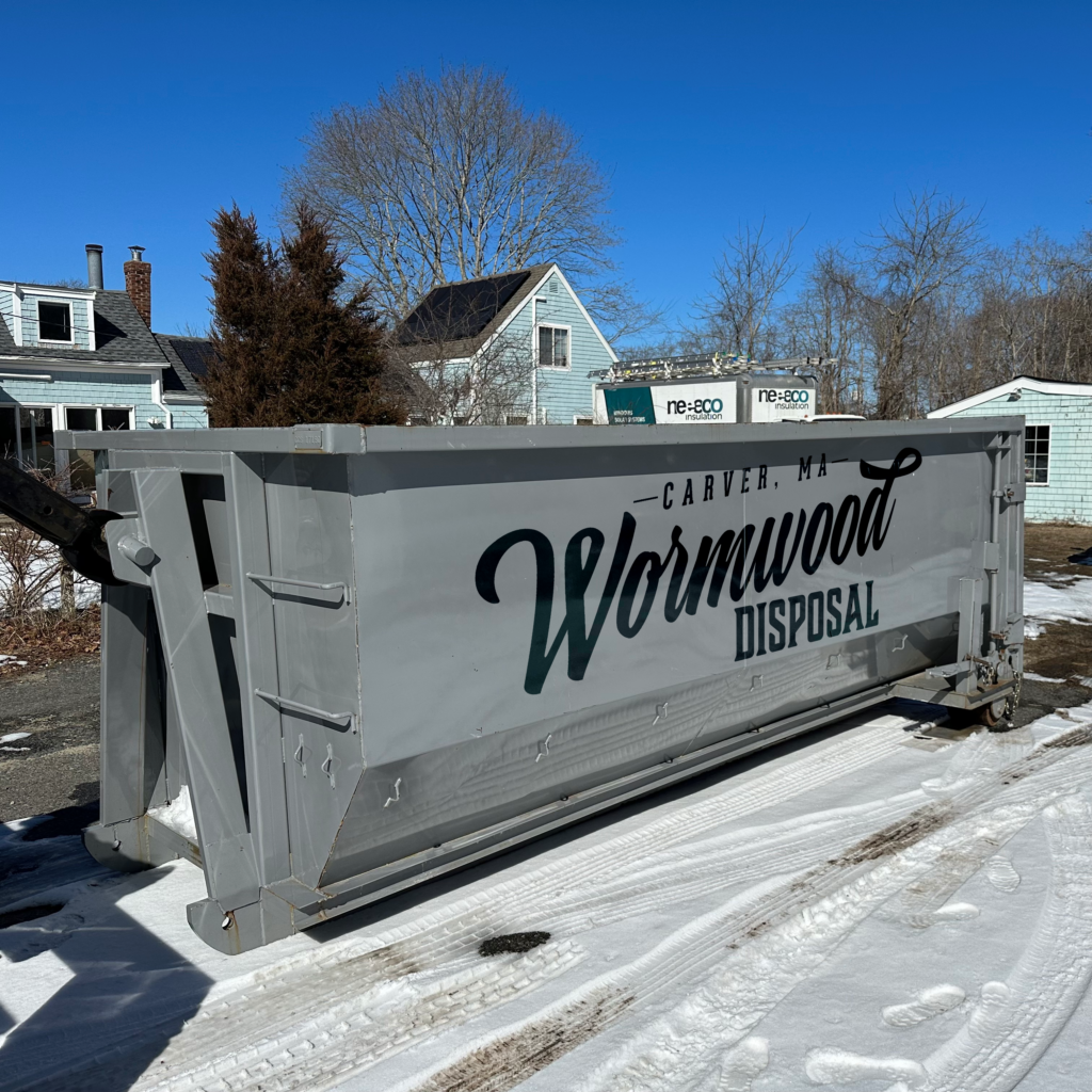 Gray 20 yard dumpster with Wormwood Disposal logo placed in a snowy driveway in Wareham