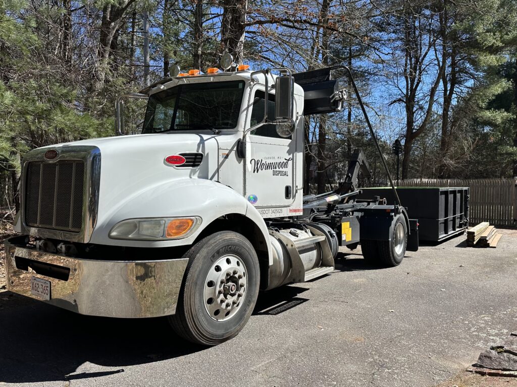 Wormwood Disposal truck picking up a 12 yard dumpster in a driveway in Taunton